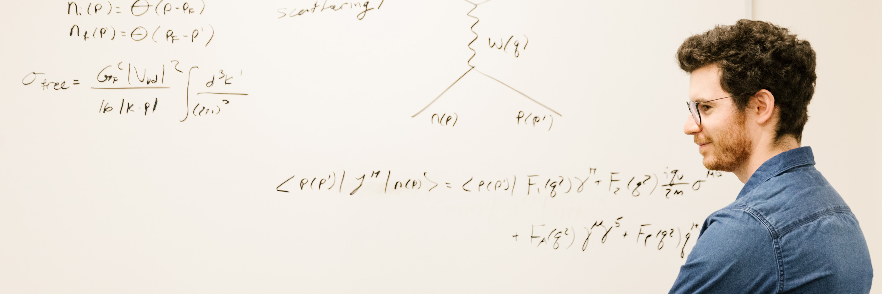Man standing in front of a white board covered in equations