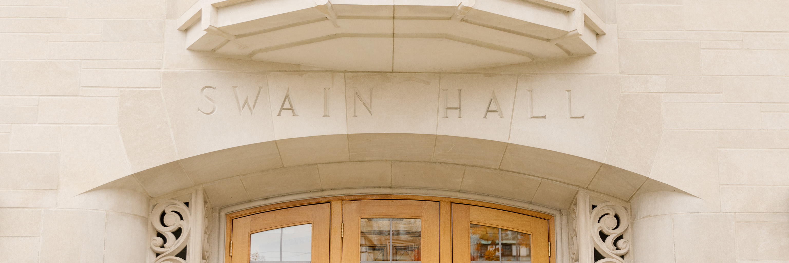 "Swain Hall" carved into a limestone arch above an exterior doorway