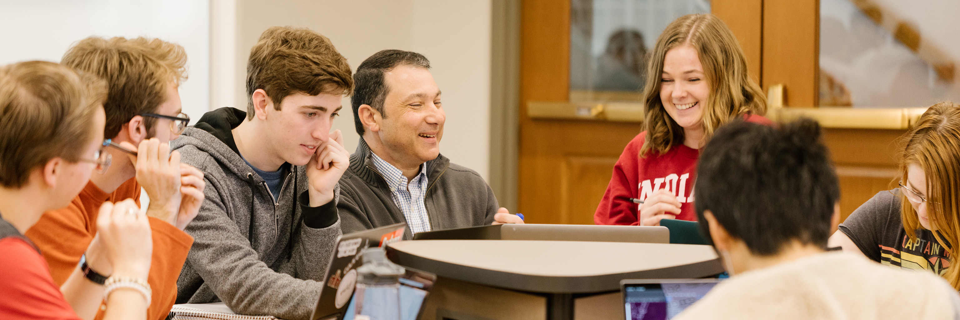 Small group of students laughing with a professor.