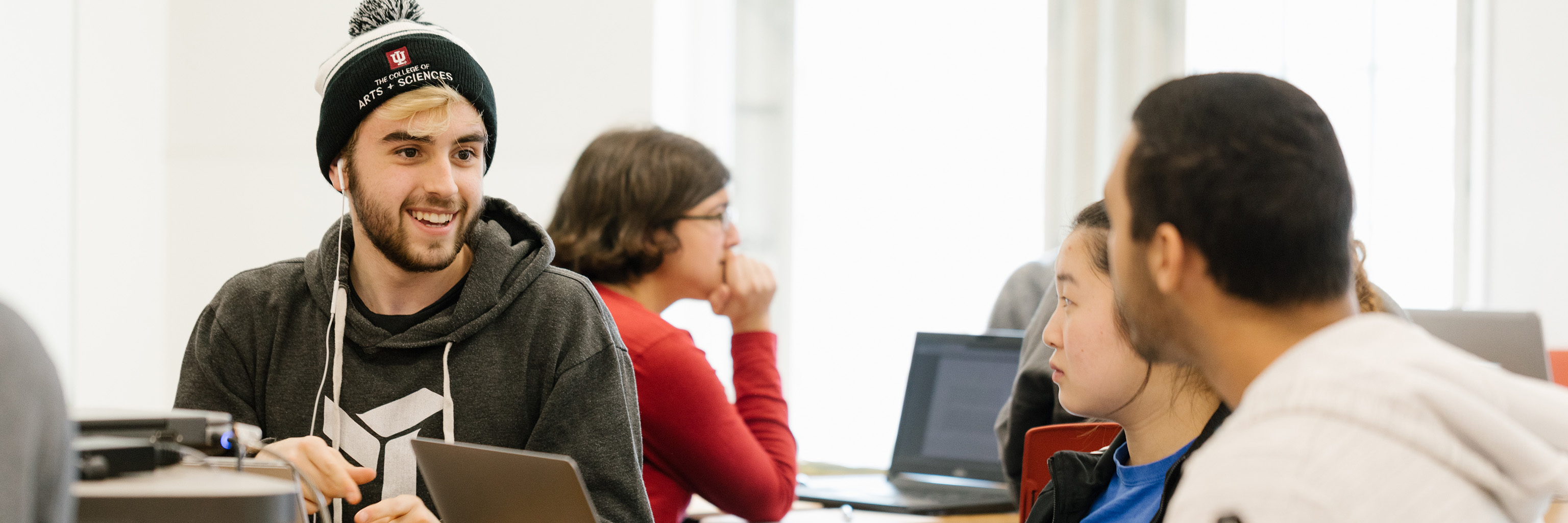 A student smiling at another student in the classroom.