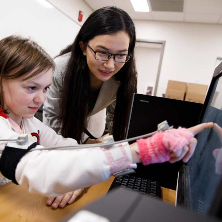 Woman working with a young girl on a computer