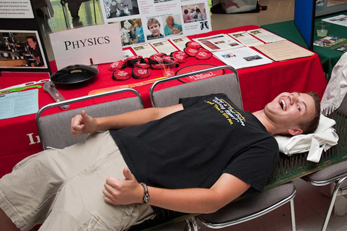 Student participating in a demonstration in front of a table for the physics department