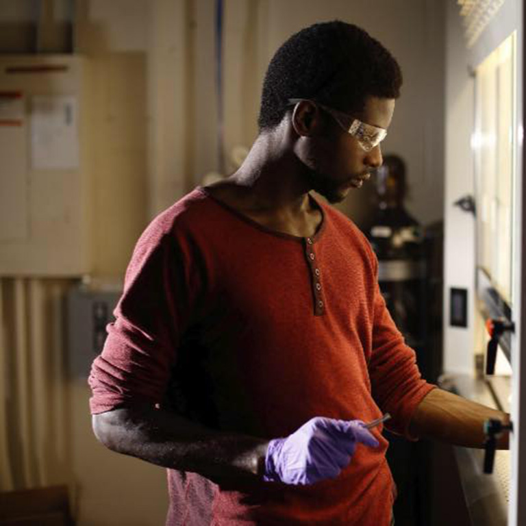 A man wearing safety glasses and gloves while he works in the lab.