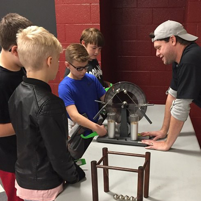 School-age children conduct experiments with physics lab equipment.
